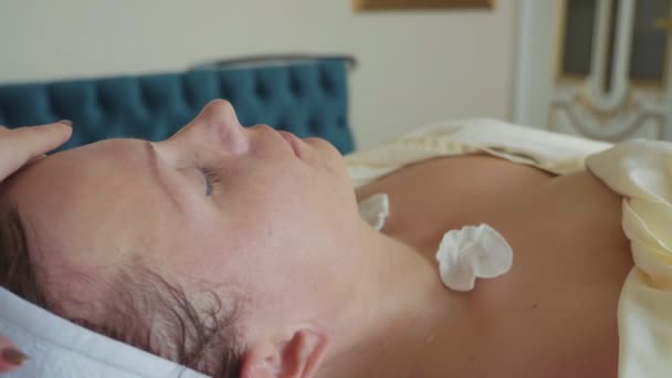 Косметолог очищает лицо женщины хлопковой губкой в салон красоты — стоковое видео