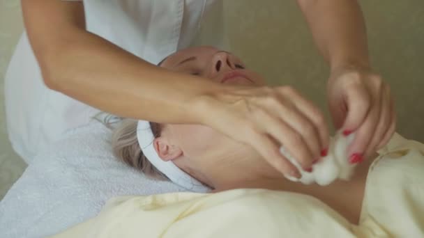 Schoonheidsspecialist is het reinigen van dames gezicht door katoen spons op spa salon — Stockvideo