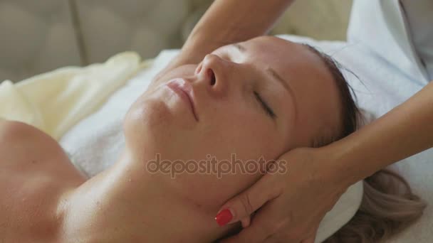 Krásná mladá žena relaxační masáži obličeje na luxusní wellness salon, detail. — Stock video