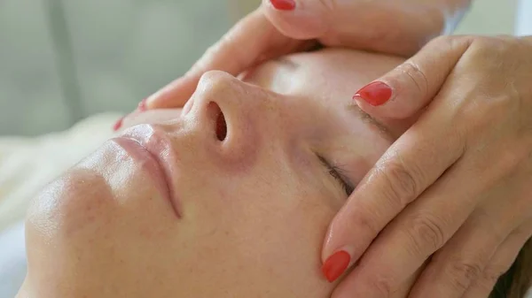 Beautiful young woman relaxing with face massage at luxury spa salon, close-up. — Stock Photo, Image