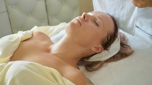 Beautiful young woman relaxing with face massage at luxury spa salon, close-up. — Stock Photo, Image