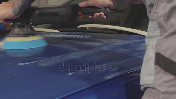 Meister poliert den tiefblauen Sportwagen per Poliermaschine in einer Autowerkstatt — Stockvideo