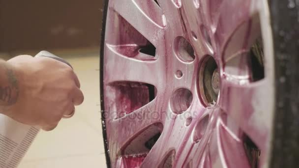 Людина використовує хімію для очищення спортивного автомобільного колеса, повільний рух — стокове відео