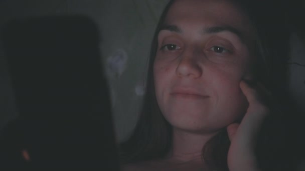 Jeune femme utilisant un téléphone portable sur le lit la nuit — Video