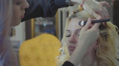 Modelleri yüzünde kapatıcı uygulayarak genç makyaj sanatçısı.