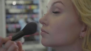 Modelleri yüzünde kapatıcı uygulayarak genç makyaj sanatçısı.