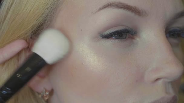 Unga makeupartist tillämpa glans på modeller ansikte. — Stockvideo