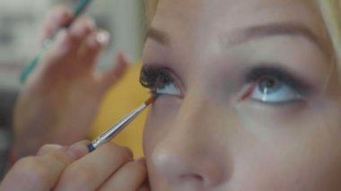 Kozmetik modelleri gözünü uygulayarak genç makyaj sanatçısı.