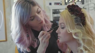 Kozmetik modelleri gözünü uygulayarak genç makyaj sanatçısı.