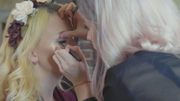 Unga makeupartist sminkning på modeller ögon. — Stockvideo