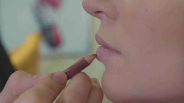 Jovem maquiador aplicando batom em modelos de lábios . — Vídeo de Stock