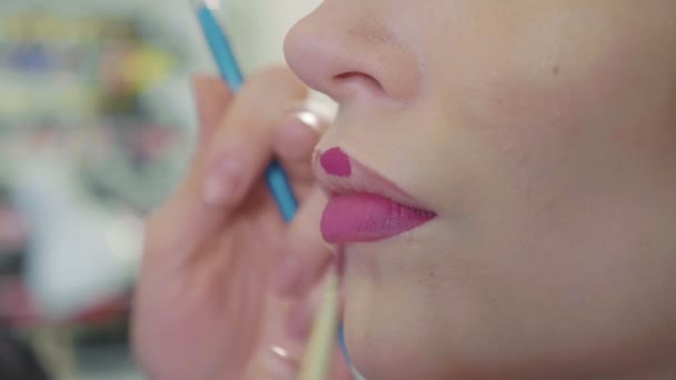 Jonge make-up artiest lippenstift toe te passen op modellen lippen. — Stockvideo