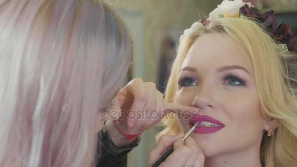 Jonge make-up artiest lippenstift toe te passen op modellen lippen. — Stockvideo