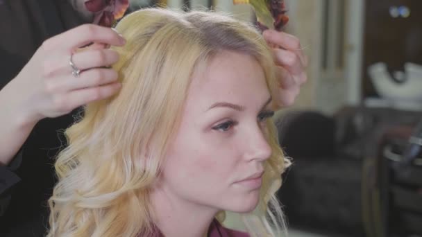 Young female barber puts a wreath to pretty blonde woman at luxury beaty salon. — Stock Video