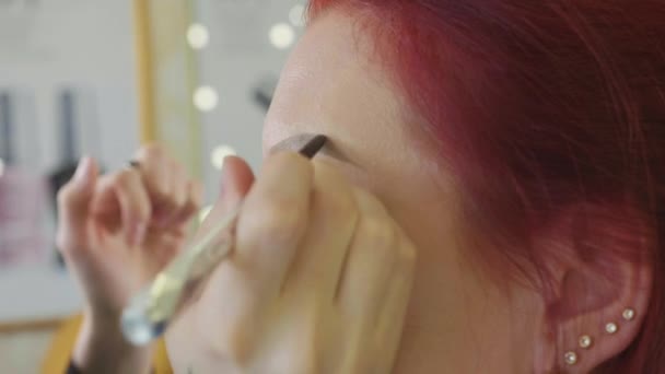 Makeup stylist gör vackra ögonbryn till ung rödhårig kvinna på skönhetssalong — Stockvideo