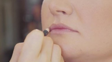 Modelleri dudaklarından ruj uygulayarak genç makyaj sanatçısı.