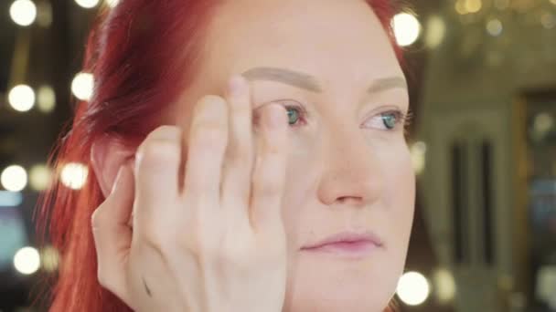 Styliste de maquillage fait de beaux sourcils à la jeune rousse femme à l'institut de beauté — Video