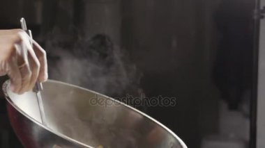 Şef çelik wok, yakın çekim ağır çekim bir omlet pişirme.