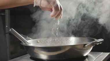 Ağır çekim wok tavada kızarmış gıda baharat Şef Close-Up dökülen.