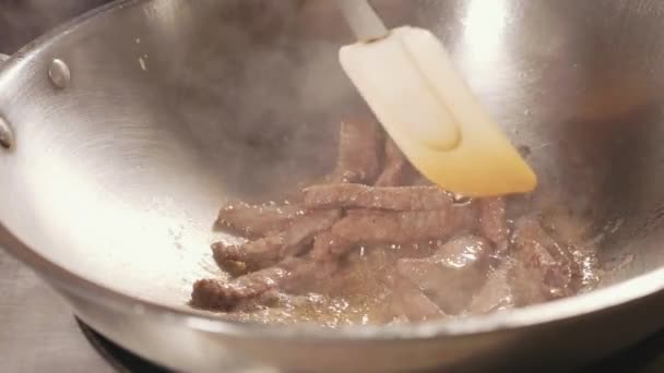 Крупный план повара, готовящего мясо на сковородке. Мясо жареное в кипящем масле, замедленная съемка — стоковое видео