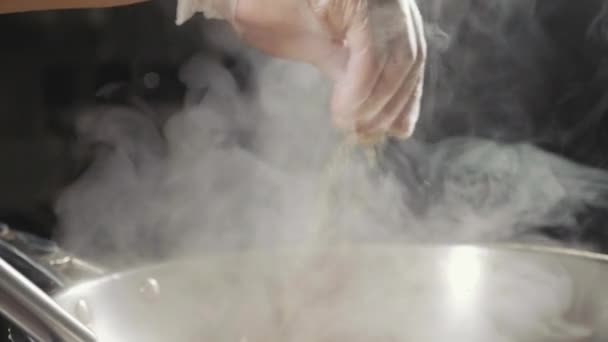 Gros plan du chef verse les assaisonnements dans les aliments frits dans une poêle à wok, au ralenti . — Video