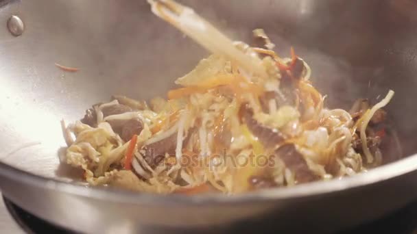 Detail kuchař vaření nudle s masem a zeleninou v pánev wok — Stock video