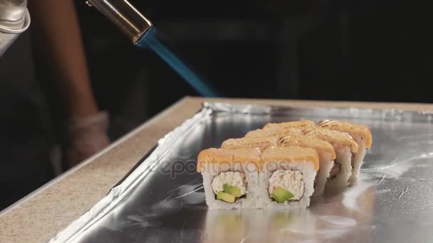 Professionale sushi chef preparare roll via fuoco in cucina commerciale, primo piano . — Video Stock