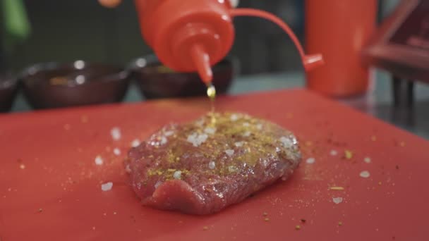 Chef marinating raw meat for preparing steak at commercial kitchen, close-up — Stock Video