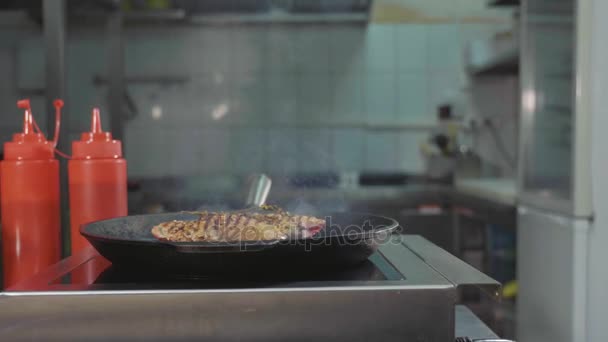 Slide slow motion of chef puts a steel press on steak of meat on a griddle pan — Stock Video