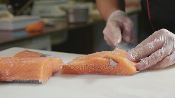 Nahaufnahme eines Sushi-Kochs in Handschuhen schneidet frischen Lachs an der Sushi-Bar. — Stockvideo
