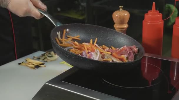 Kocken fries olika grönsaker och kött med smör på en varm stekpanna — Stockvideo