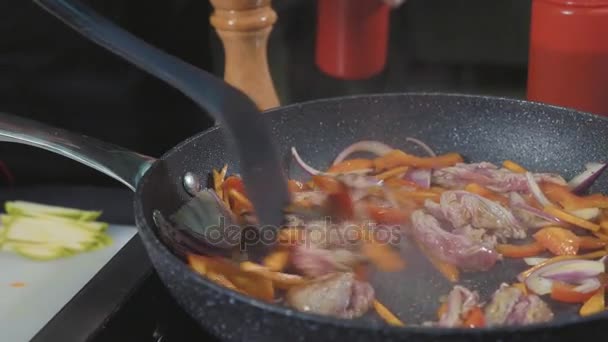 Szakács fries különböző zöldségek és a hús a egy forró serpenyőben vajjal — Stock videók