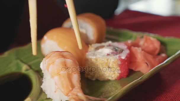 Woman dips sushi with shrimp in sauce with chopsticks at japanese restaurant. — Stock Video