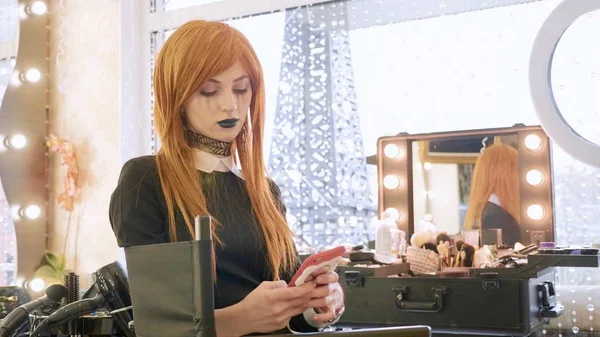 Młoda piękna dziewczyna z halloween makijaż przy użyciu inteligentnego telefonu w salonie kosmetycznym — Zdjęcie stockowe