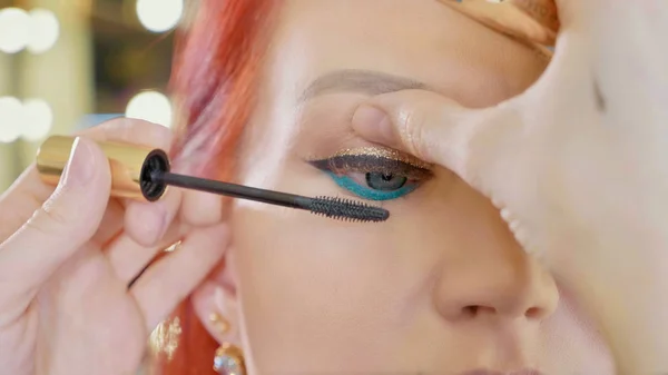 Make-up artist applying makeup to models eye. Close up view.