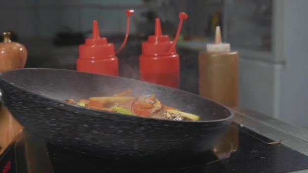 Kocken fries olika grönsaker och kött med smör på en varm stekpanna — Stockvideo
