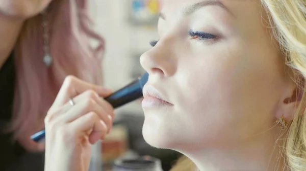 Jonge make-up artiest concealer toepassen op modellen gezicht. — Stockfoto