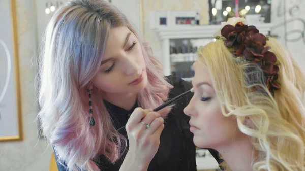 Jonge make-up artiest cosmetica toe te passen op modellen ogen. — Stockfoto