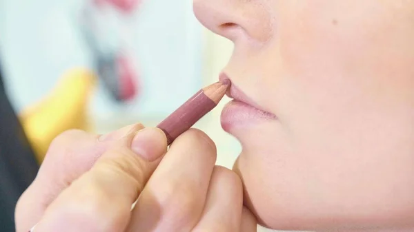 Jonge make-up artiest lippenstift toe te passen op modellen lippen. — Stockfoto