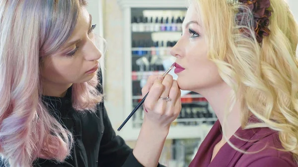 Jonge make-up artiest lippenstift toe te passen op modellen lippen. — Stockfoto