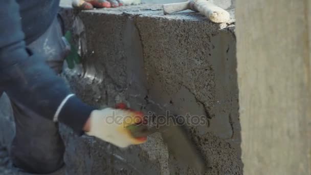 Trabalhador da construção constrói parede de tijolo, vista close-up no canteiro de obras — Vídeo de Stock