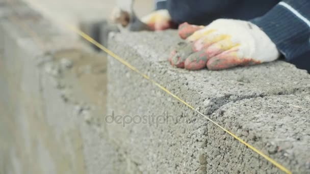 Trabajador de la construcción construye pared de ladrillo, vista de primer plano en el sitio de construcción — Vídeos de Stock