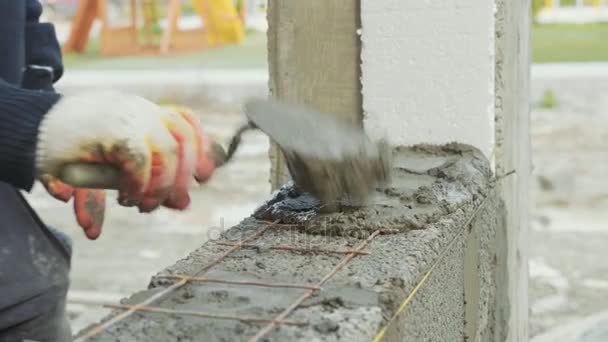 Trabalhador da construção constrói parede de tijolo, vista close-up no canteiro de obras — Vídeo de Stock