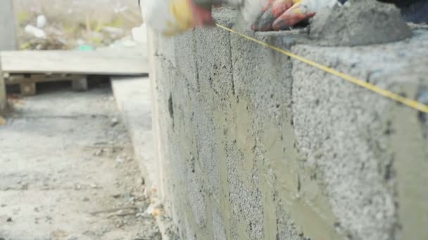 Trabajador de la construcción construye pared de ladrillo, vista de primer plano en el sitio de construcción — Vídeo de stock