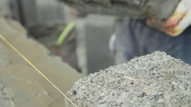 Trabalhador da construção constrói parede de tijolo, vista close-up no canteiro de obras — Vídeo de Stock