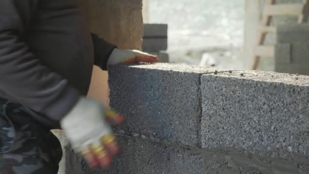 Trabajador de la construcción construye pared de ladrillo, vista de primer plano en el sitio de construcción — Vídeos de Stock