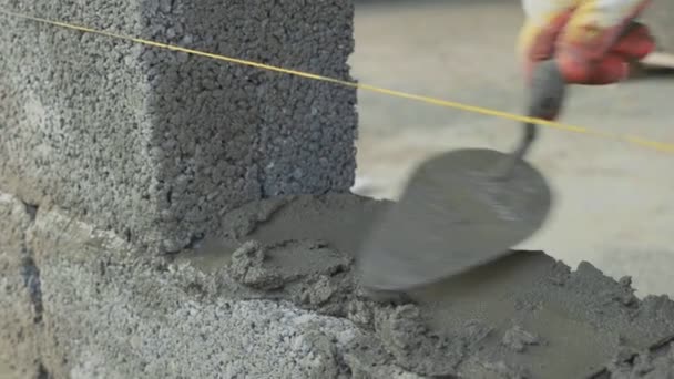 Trabajador de la construcción construye pared de ladrillo, vista de primer plano en el sitio de construcción — Vídeos de Stock