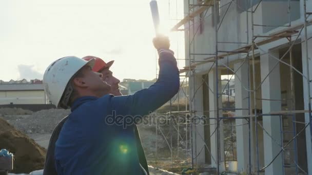 Byggnadsarbetare och ingenjör pratar på byggarbetsplatsen webbplats — Stockvideo