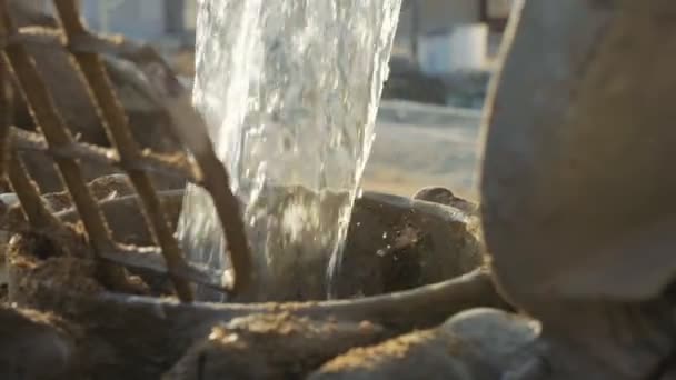 Junger weißer Arbeiter gießt Wasser in einen Betonmischer, Nahaufnahme, Zeitlupe. — Stockvideo