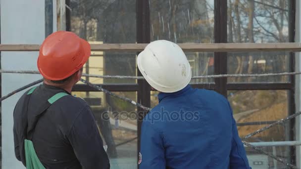 Travailleur de la construction et ingénieur parlant sur le chantier de construction, vue arrière . — Video